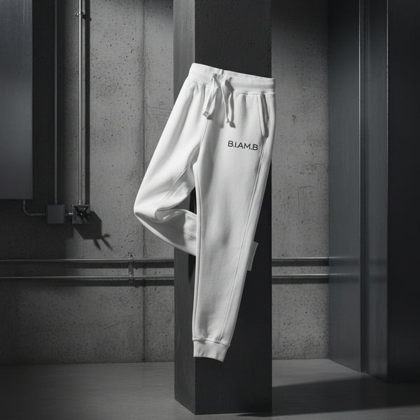 Close-up front view of white B.I.AM.B sweatpants with a drawstring waist and small logo on the right thigh, displayed flat on a plain background.