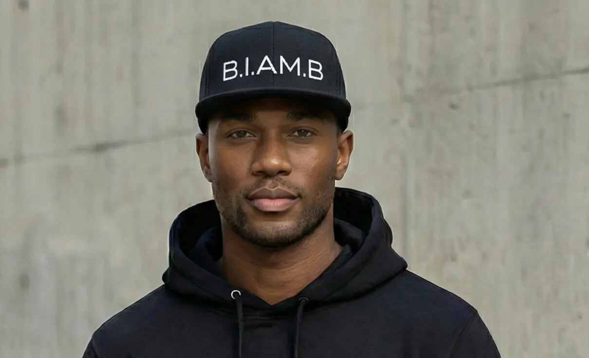 Model wearing B.I.AM.B black snapback hat with black hoodie lifestyle portrait streetwear Because I Am Black brand
