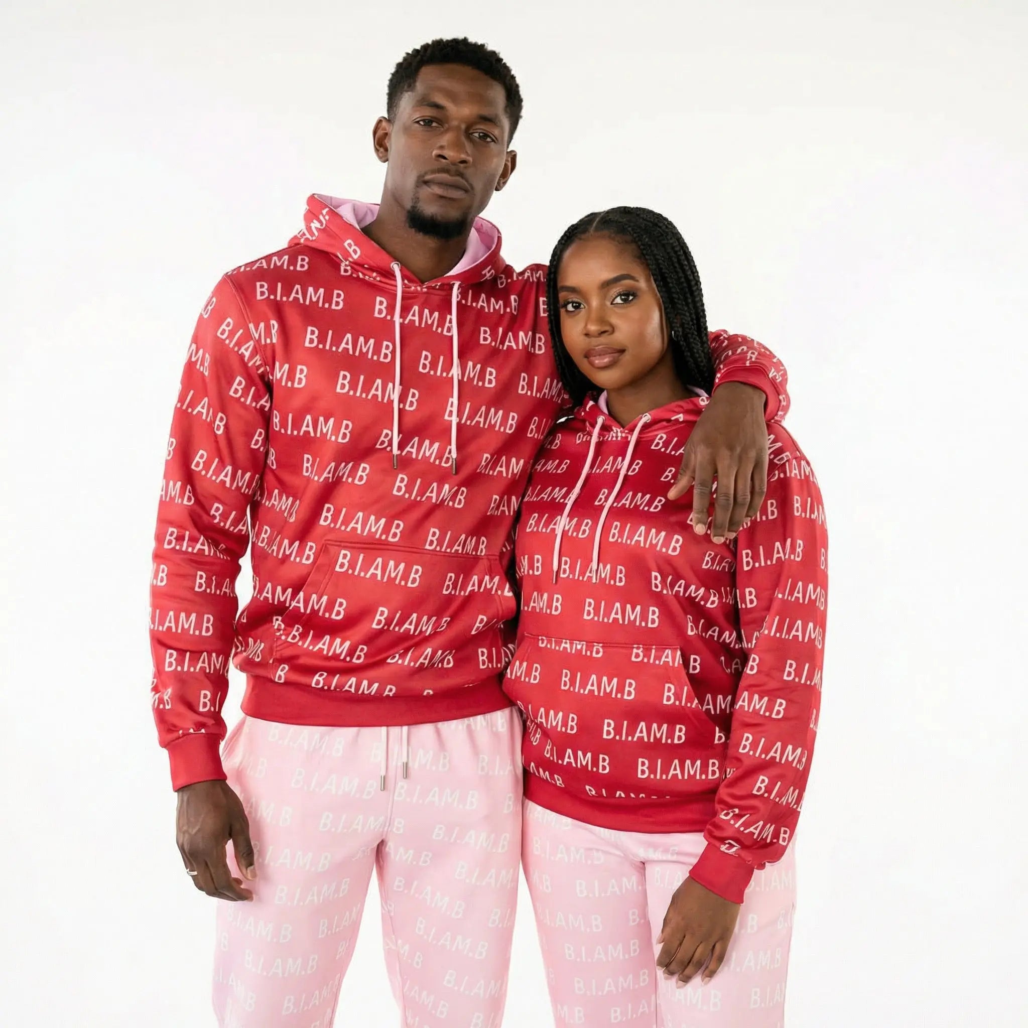 Models wearing red and pink B.I.AM.B reversible print hoodie and jogger set in an indoor urban setting